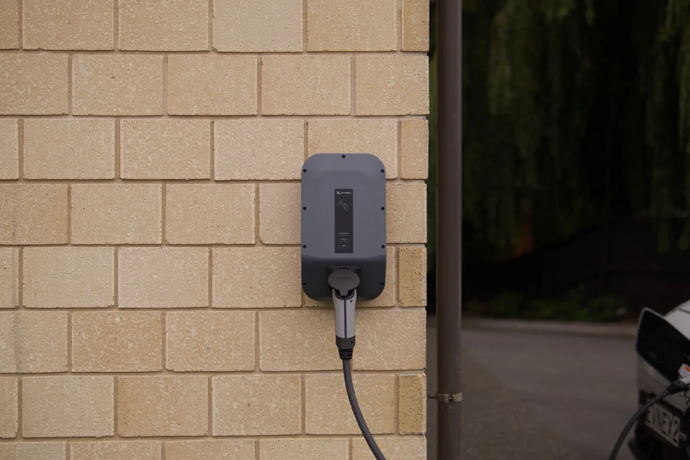 Wall-mounted electric vehicle charger installed on an exterior brick wall